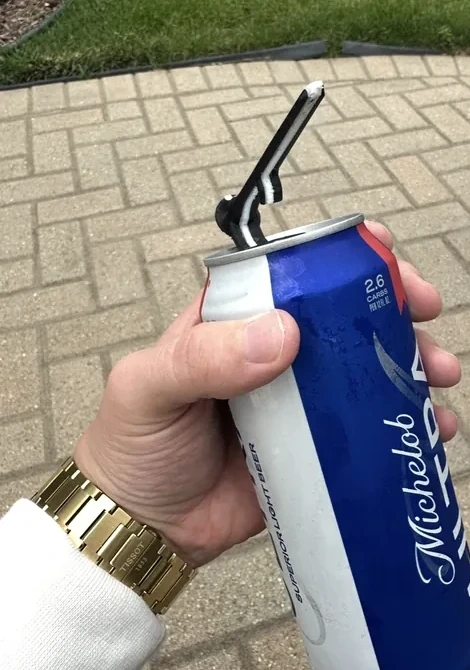 Real black Shotgun Start Tee opening the pull tab of a beverage can