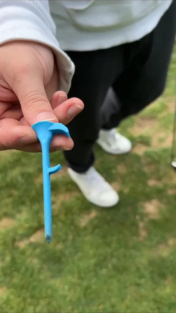 Golfer holding a blue Shotgun Start Tee on the course