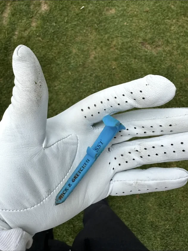 Real blue Shotgun Start Tee with customized lettering, displayed on a golf glove