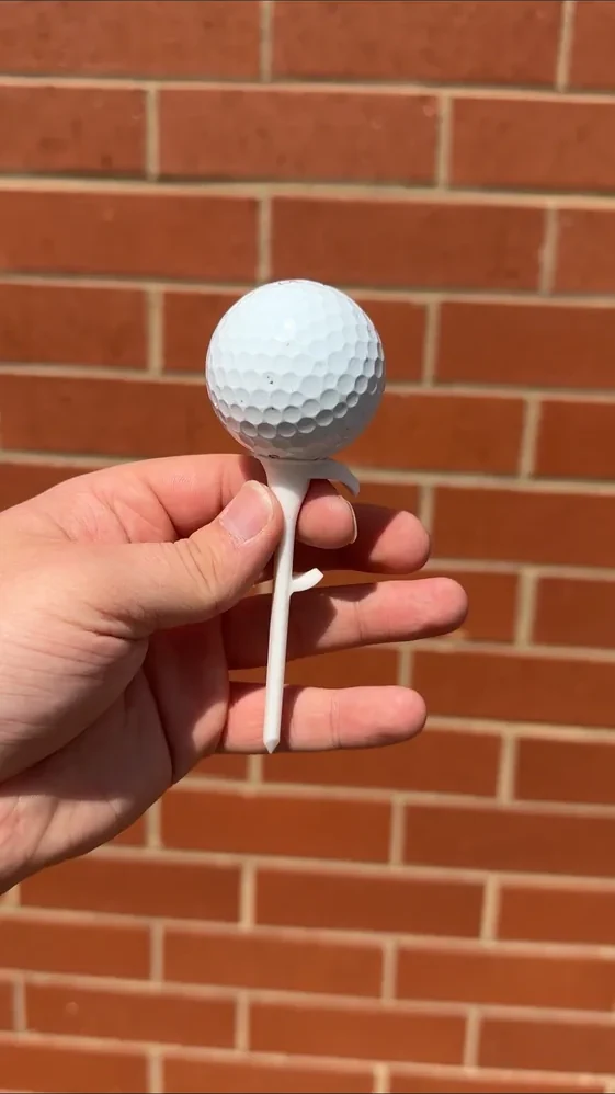 Actual white ball on the real Shotgun Start Tee held in a hand