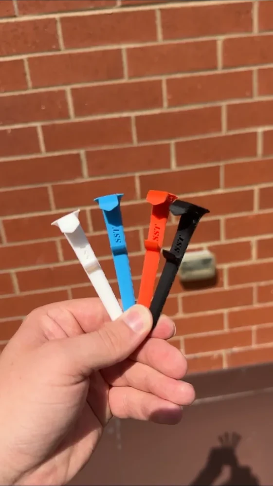 Hand holding several real colorful Shotgun Start Tees