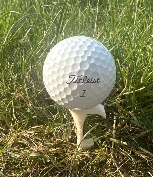 White Shotgun Start Tee holding a golf ball in real grass